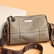 Borsa a tracolla in pelle marrone chiaro con cuciture bianche, cerniera superiore e tracolla regolabile con motivo floreale. Elegante e versatile.