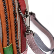 Primo piano di una borsa multicolore in pelle con cerniere e moschettone in metallo, design moderno e dettagli artigianali.