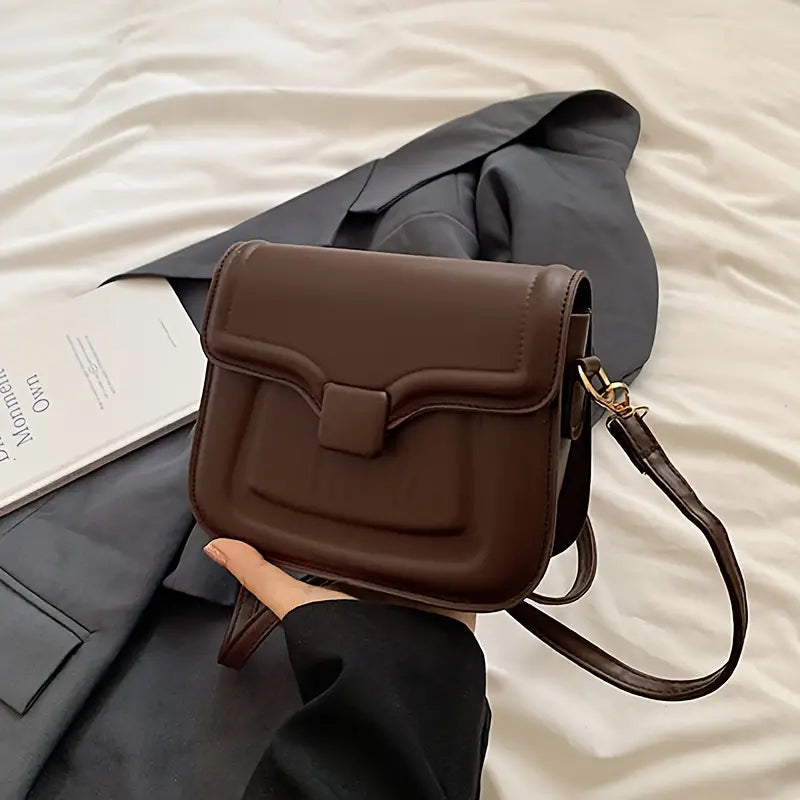 Borsa a tracolla marrone in pelle su giacca grigia, design elegante e moderno, perfetta per moda donna, accessorio versatile e chic.