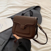 Borsa a tracolla marrone in pelle su giacca grigia, design elegante e moderno, perfetta per moda donna, accessorio versatile e chic.