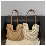Due borse a maglia in paglia beige e bianca con manici in pelle marrone su divano nero. Eleganti, estive, perfette per lo shopping o la spiaggia.