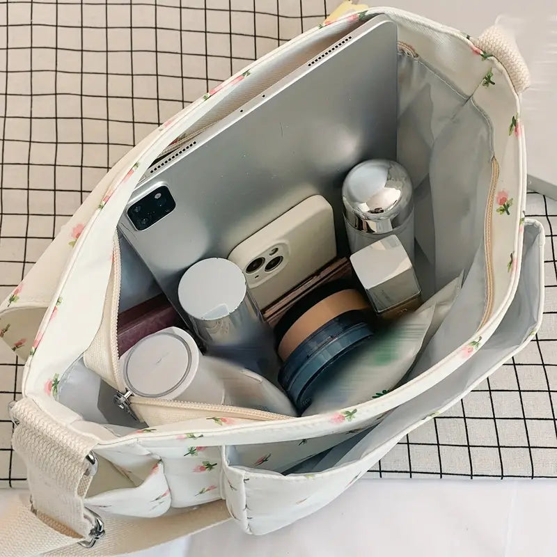 Borsa a tracolla bianca con motivo floreale, contenente tablet, smartphone, cosmetici e accessori. Ideale per organizzazione e stile quotidiano.