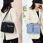 Due borse a tracolla da donna in tessuto, una nera e una grigia, indossate su giacca beige. Design elegante, tasche multiple, moda femminile.