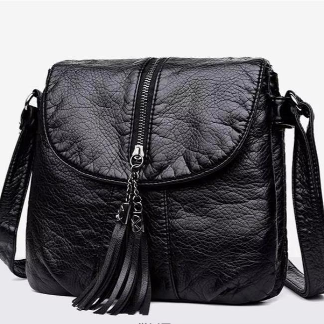 Borsa a tracolla in pelle nera con zip centrale e nappine decorative, design elegante e moderno, ideale per moda femminile e uso quotidiano.