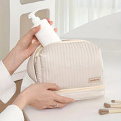 Borsa cosmetica beige con dispenser bianco, design trapuntato, chiusura a zip, ideale per organizzare prodotti di bellezza e accessori da viaggio.