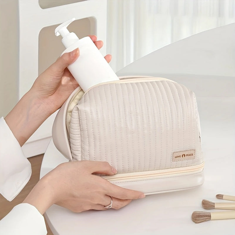 Borsa cosmetica beige con dispenser bianco, design trapuntato, chiusura a zip, ideale per organizzare prodotti di bellezza e accessori da viaggio.