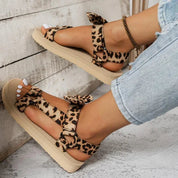 Sandali donna leopardati con zeppa, cinturini regolabili, indossati con jeans chiari. Scarpe estive moda, comode e trendy.