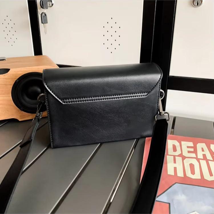 Borsa a tracolla nera in pelle su tavolo, design elegante e moderno, perfetta per moda donna. Accessorio versatile per ogni occasione.