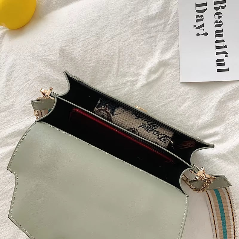 Borsa a tracolla verde chiaro aperta, con interno visibile e accessori. Design elegante, perfetta per moda femminile e uso quotidiano.