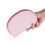 Astuccio rosa a mezzaluna in mano, chiusura con cerniera, ideale per cosmetici o accessori. Design compatto e portatile.