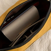 Borsa gialla aperta con portafoglio grigio all'interno, occhiali da sole e smartphone. Accessori moda donna, eleganza e praticità.