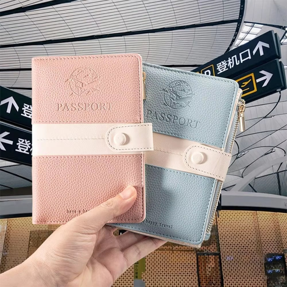 Due portapassaporti in pelle rosa e azzurro con chiusura a bottone, tenuti in mano in un aeroporto moderno. Accessori viaggio eleganti e funzionali.