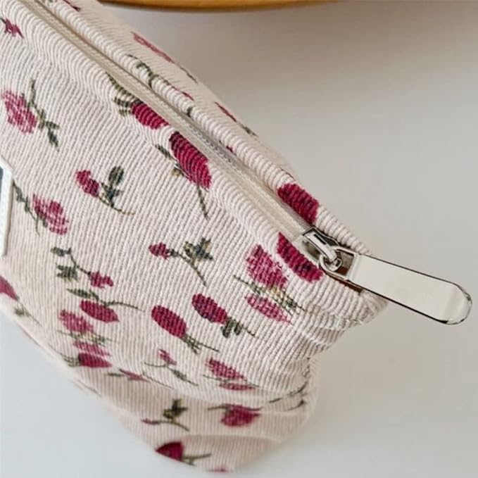 Astuccio in tessuto floreale con cerniera, motivo rose rosse su sfondo beige. Accessorio moda elegante, ideale per cosmetici o piccoli oggetti.