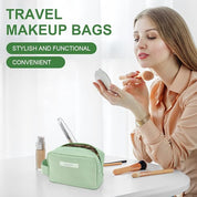 Donna che applica trucco con specchio, accanto a borsa trucco da viaggio verde su tavolo bianco. Include pennelli e fondotinta. Elegante e funzionale.