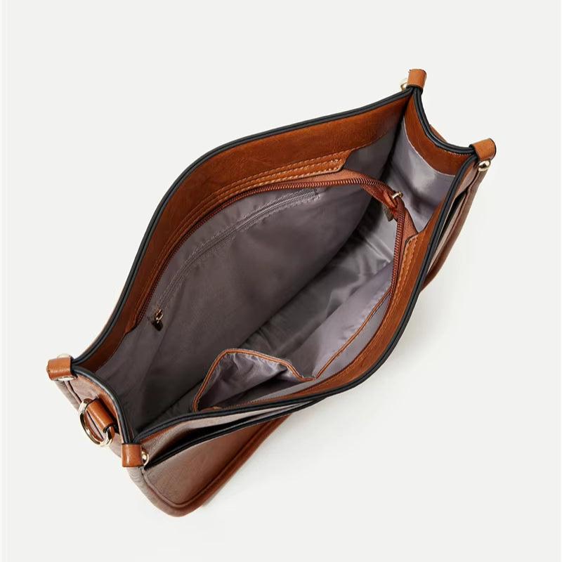 Borsa a tracolla in pelle marrone con interno spazioso, tasca con zip e fodera grigia. Accessorio moda elegante e funzionale per donna.