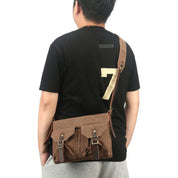 Uomo con borsa a tracolla in tela marrone, doppia fibbia, stile casual. Ideale per viaggi, lavoro, tempo libero. Accessorio moda maschile.