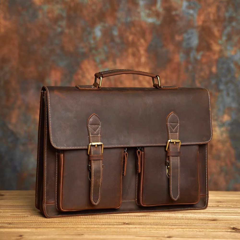 Elegante cartella in pelle marrone su tavolo di legno, con fibbie dorate e tasche frontali. Accessorio di moda per uomo, ideale per lavoro e ufficio.