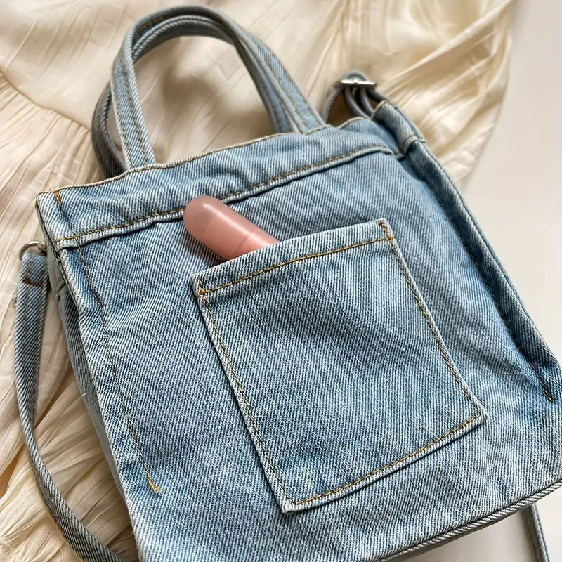 Borsa a tracolla in denim con tasca frontale, contenente un rossetto rosa. Design casual, perfetta per moda quotidiana e accessori femminili.