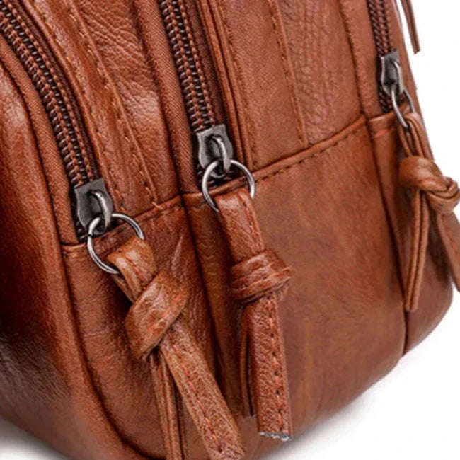 Borsa a tracolla in pelle marrone con cerniere multiple e dettagli in metallo. Design elegante e pratico per moda e accessori uomo e donna.