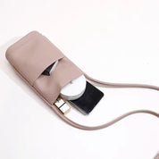 Borsa a tracolla in pelle rosa con tasca aperta, contenente smartphone, rossetto e specchietto. Accessorio moda donna elegante e pratico.