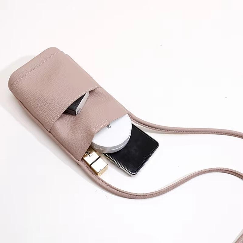 Borsa a tracolla in pelle rosa con tasca aperta, contenente smartphone, rossetto e specchietto. Accessorio moda donna elegante e pratico.