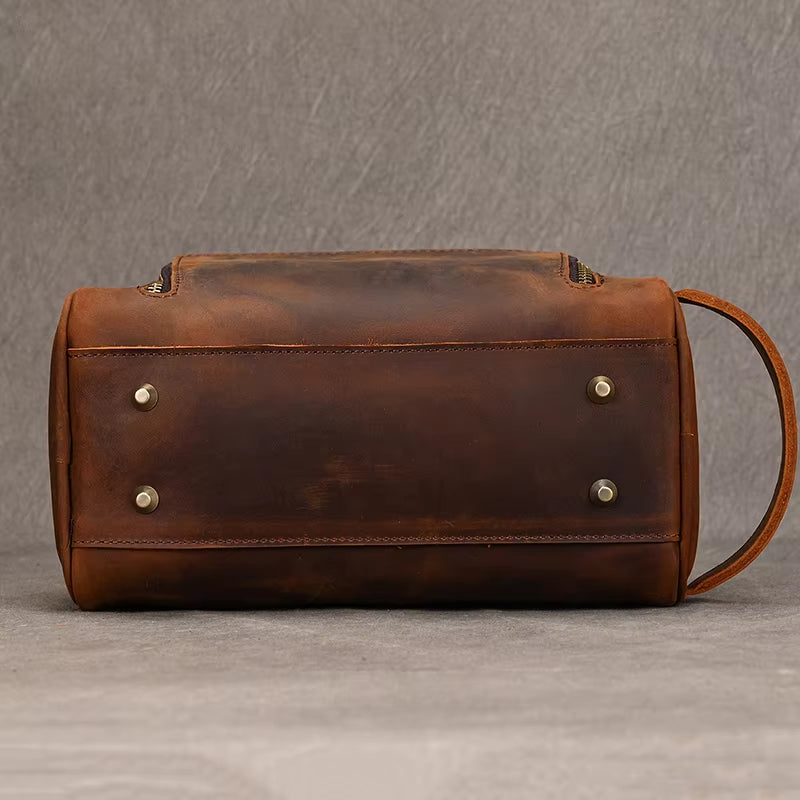 Borsa in pelle marrone vintage con base rinforzata e piedini metallici, manico laterale. Elegante e resistente, ideale per viaggi e uso quotidiano.
