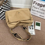 Borsa a tracolla beige su tappeto marrone, accanto a calendario 2023 e termometro digitale. Design casual, ideale per uso quotidiano.
