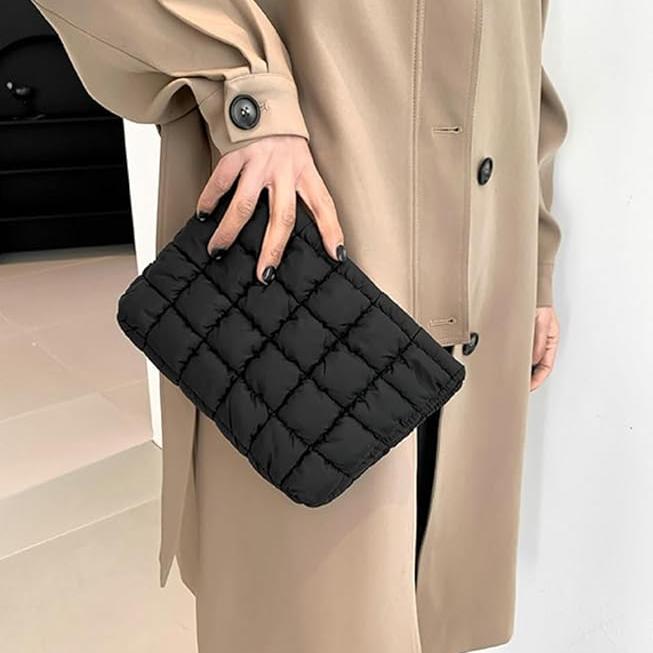 Donna con cappotto beige tiene una pochette nera trapuntata. Moda elegante, accessori femminili, borsa a mano chic.