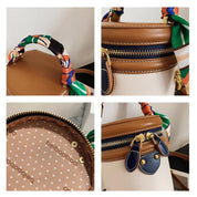 Borsa a secchiello in pelle marrone e bianca con manico in tessuto colorato, dettagli in metallo dorato, chiusura a zip, interno a pois.