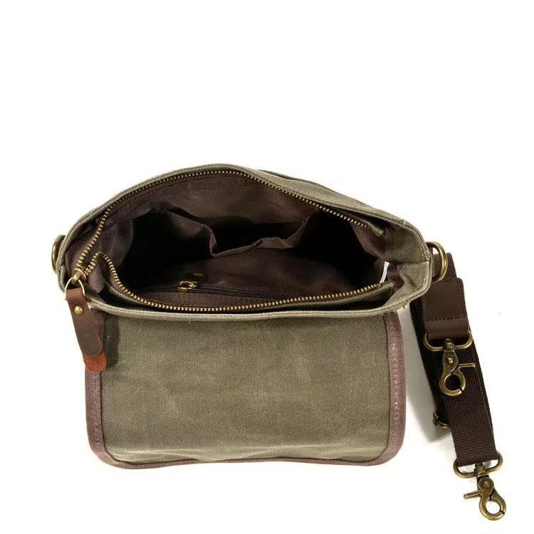 Borsa a tracolla in tela verde militare con dettagli in pelle marrone, tasche interne, cerniera superiore e tracolla regolabile. Accessorio moda uomo.