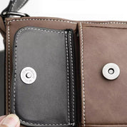 Portafoglio in pelle marrone e nera aperto, con chiusura a bottone e cuciture bianche. Design elegante e funzionale per uomo o donna.