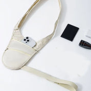 Marsupio a tracolla beige con smartphone in tasca, portafoglio nero e chiavi su sfondo bianco. Accessori moda pratici e funzionali per viaggi.