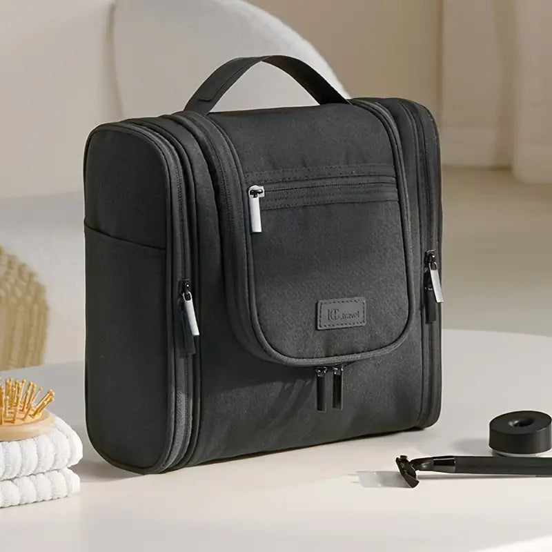 Borsa da toilette nera con manico, zip multiple e tasche, ideale per viaggi. Design elegante e funzionale, perfetta per organizzare accessori bagno.