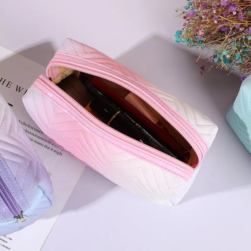 Astuccio da trucco rosa e bianco con cerniera, contenente cosmetici, su sfondo chiaro con fiori secchi. Accessorio moda donna elegante e pratico.