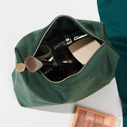 Astuccio verde per trucchi aperto, contenente pennelli e cosmetici. Accessori make-up essenziali, ideale per organizzare prodotti di bellezza.