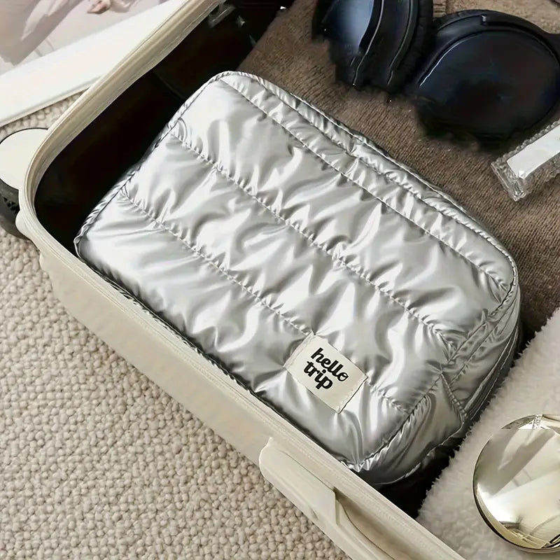 Valigia aperta con borsa da viaggio argentata "hello trip", cuffie nere e accessori. Ideale per viaggi, organizzazione bagagli, accessori viaggio.
