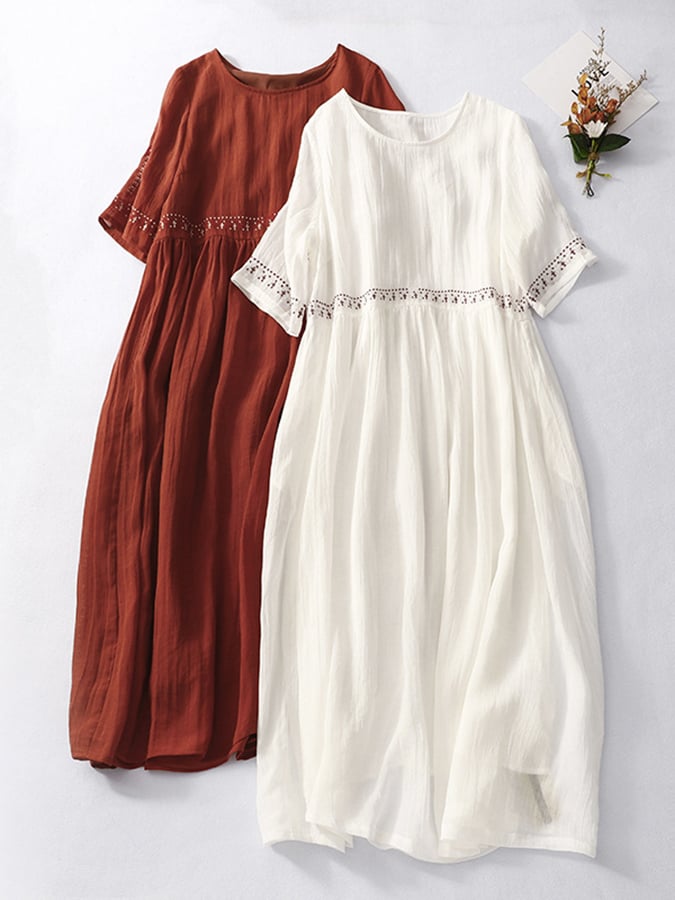 Abiti lunghi estivi in cotone, uno bianco e uno rosso, con dettagli in pizzo sulle maniche e in vita, su sfondo chiaro. Moda donna elegante.