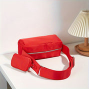 Marsupio rosso in tessuto con cerniera su tavolo bianco, design moderno, ideale per viaggi e attività all'aperto. Accessorio moda unisex.