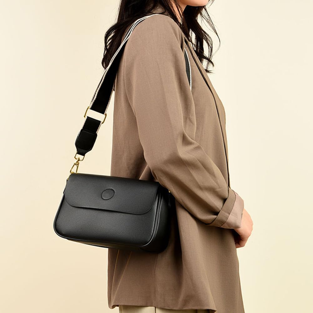 Borsa a tracolla nera in pelle, indossata da una donna con giacca marrone. Design elegante, ideale per moda femminile e accessori di tendenza.