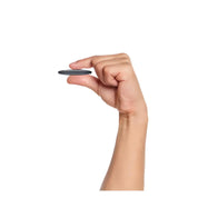 Mano che tiene un piccolo dispositivo rotondo nero, compatto e portatile. Ideale per tecnologia smart, accessori elettronici, gadget innovativi.