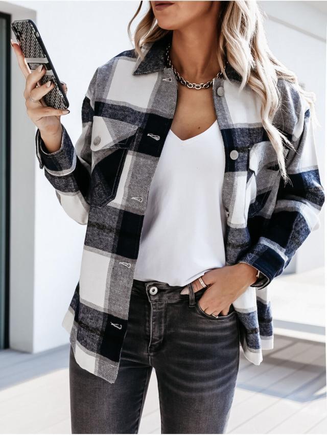 Donna con camicia a quadri bianca e nera, t-shirt bianca e jeans grigi, tiene uno smartphone. Moda casual autunnale, outfit trendy.
