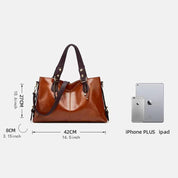Borsa a mano in pelle marrone, dimensioni 42x27x8 cm, con manici scuri. Confronto dimensioni con iPhone Plus e iPad. Elegante e spaziosa.