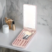 Set di pennelli trucco con specchio LED portatile su sfondo marmo. Include pennelli cosmetici di diverse dimensioni, ideale per viaggi e uso quotidiano.