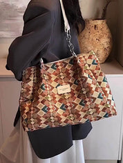 Borsa a tracolla multicolore con motivo geometrico, indossata da una persona in giacca grigia. Accessorio moda elegante e versatile.