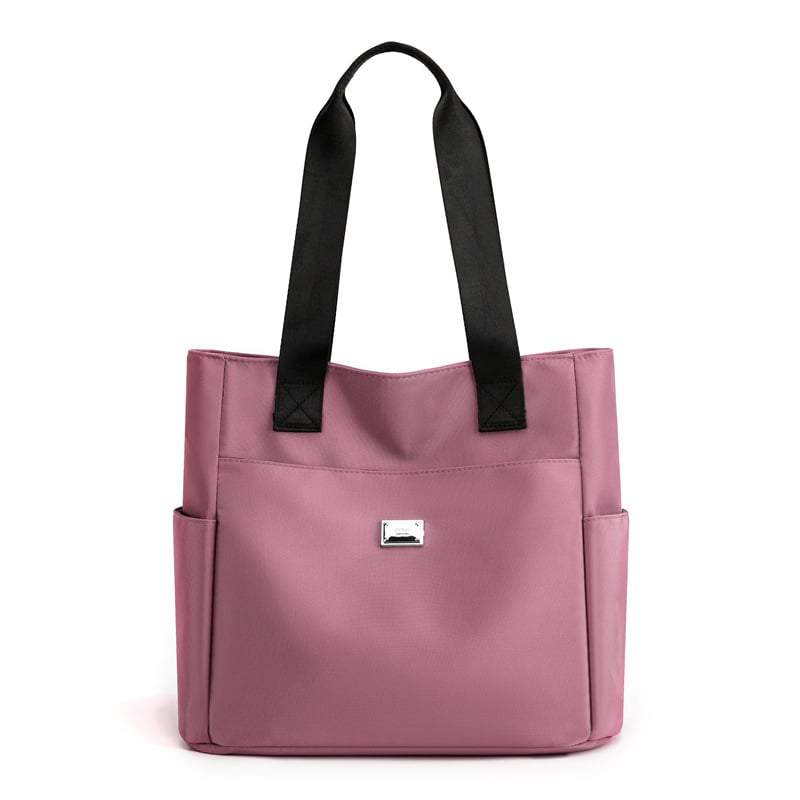 Borsa tote rosa in tessuto con manici neri, tasche laterali e logo frontale. Elegante e pratica per uso quotidiano. Accessorio moda donna.