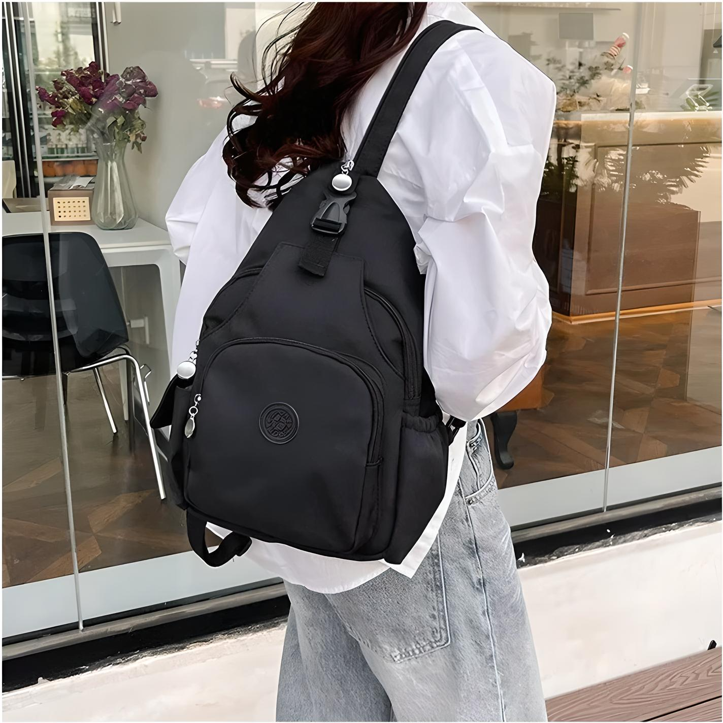 Zaino nero casual in nylon, indossato da una persona con camicia bianca e jeans, davanti a una vetrina. Design moderno e pratico per uso quotidiano.