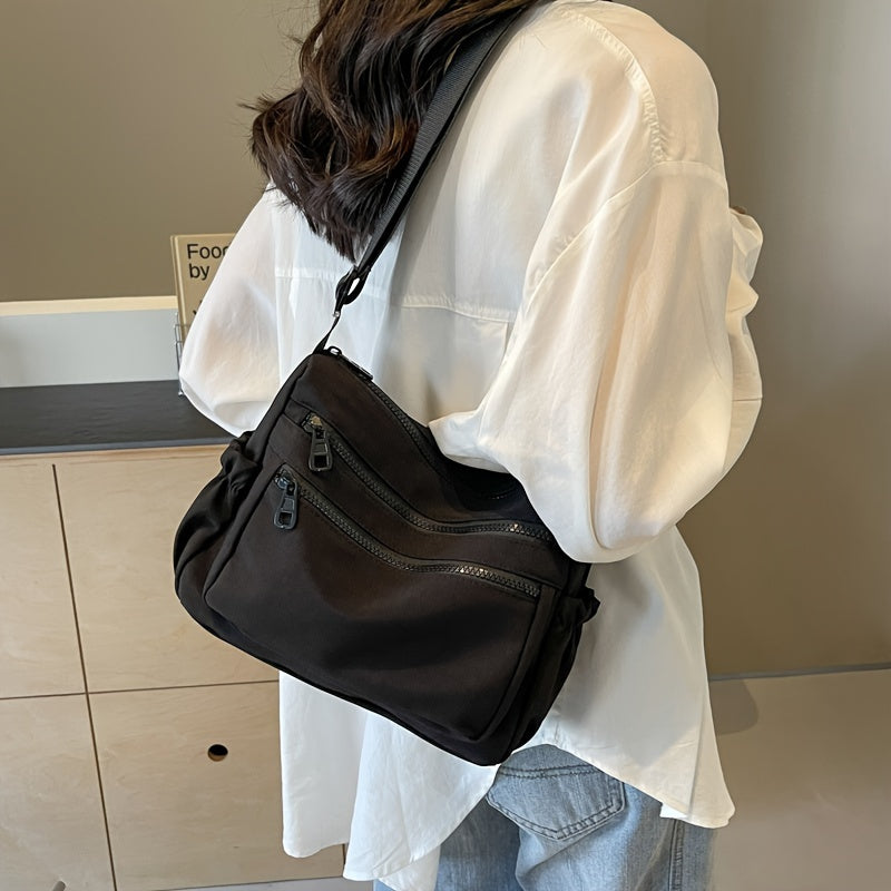 Donna con camicia bianca indossa borsa a tracolla nera con tasche multiple, stile casual. Accessorio moda femminile, pratico e versatile.