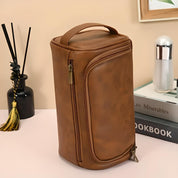Borsa da viaggio in pelle marrone con cerniera, manico superiore, design elegante. Accessorio moda, ideale per organizzare cosmetici e articoli da toeletta.