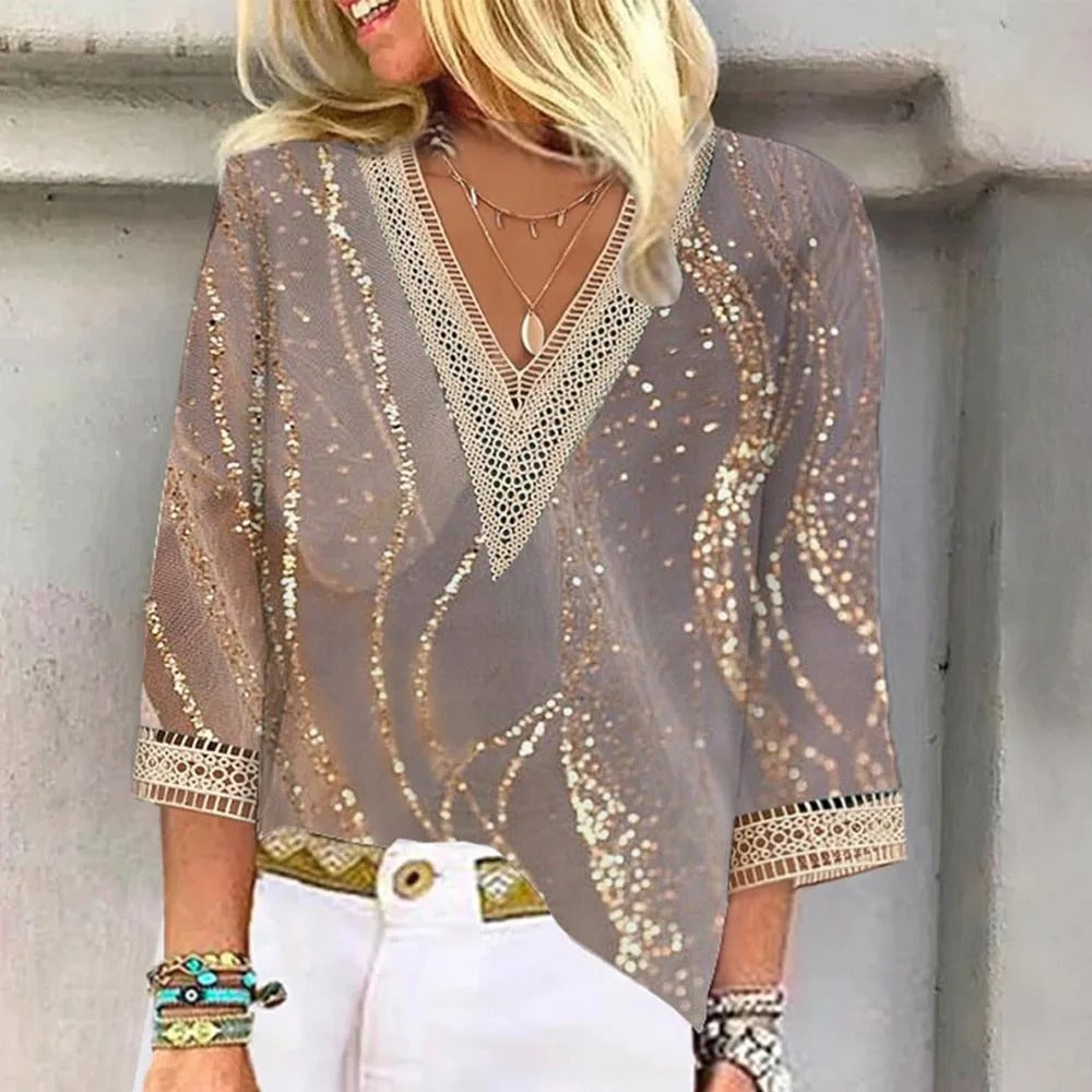 Blusa donna elegante con paillettes dorate, maniche a tre quarti, scollo a V, dettagli in pizzo, abbinata a pantaloni bianchi. Moda femminile chic.