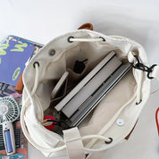 Borsa bianca aperta con laptop, libri e accessori. Vista dall'alto, ideale per studenti e professionisti. Design pratico e spazioso.
